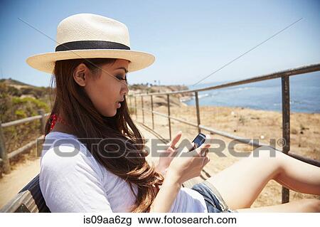 Stock Image - Young woman using cellphone, Palos Verdes, California, USA. Fotosearch