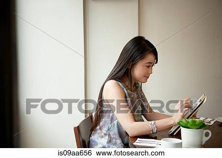 Young woman using digital tablet in restaurant View Large Photo Image Stock Photograph - Young woman using digital tablet in restaurant. Fotosearch