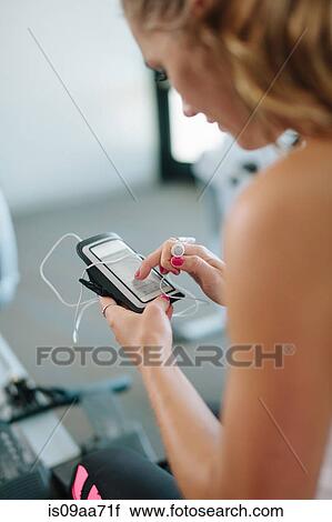 Young woman using mobile while exercising in gym View Large Photo Image Stock Image - Young woman using mobile while exercising in gym. Fotosearch