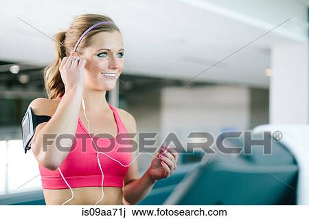 Young woman with smartphone armband and earplugs View Large Photo Image Stock Image - Young woman with smartphone armband and earplugs. Fotosearch