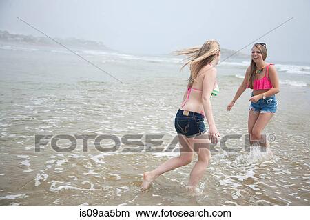 Young women playing in tide on beach View Large Photo Image Picture - Young women playing in tide on beach. Fotosearch