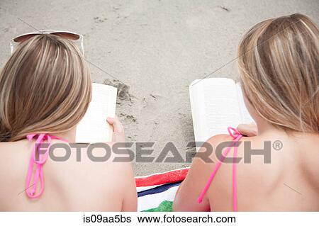 Stock Photograph - Young women reading books on beach. Fotosearch