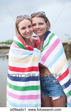 Stock Image - Young women wrapped in beach towel, portrait. Fotosearch