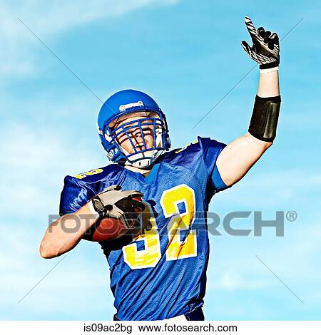 Stock Image - American footballer holding ball with arm raised. Fotosearch