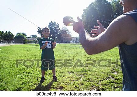 Stock Photo - Boy and grandfather playing catch with football. Fotosearch