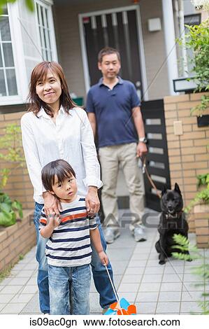 Picture - Boy and parents outside home with pet dog. Fotosearch