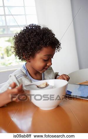 Boy eating breakfast and using digital tablet View Large Photo Image Stock Image - Boy eating breakfast and using digital tablet. Fotosearch