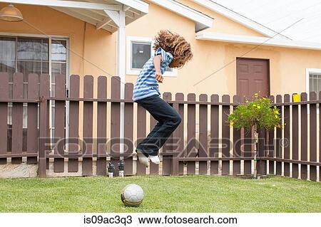 Stock Image - Boy jumping over football. Fotosearch