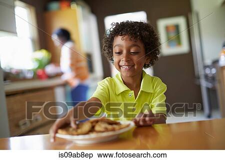 Stock Photography - Boy looking at plate of cookies. Fotosearch