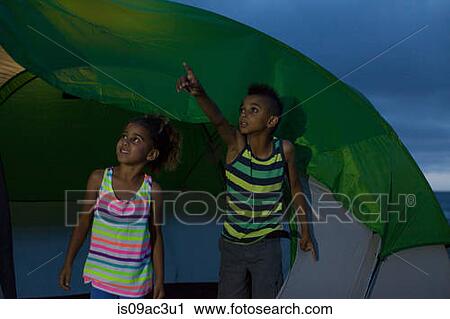 Stock Image - Brother and sister in tent, boy pointing. Fotosearch