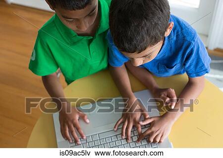 Brothers typing on laptop View Large Photo Image Stock Photo - Brothers typing on laptop. Fotosearch