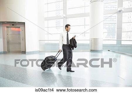 Picture - Businessman pulling wheeled suitcase. Fotosearch