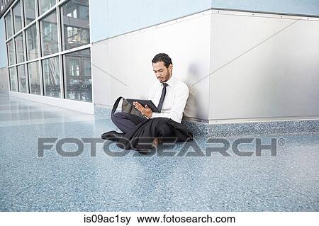 Businessman sitting on floor using digital tablet View Large Photo Image Stock Photo - Businessman sitting on floor using digital tablet. Fotosearch