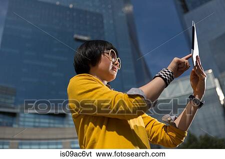 Stock Photograph - Casual businesswoman using table outside office buildings. Fotosearch