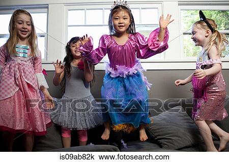 Stock Image - Children dancing and jumping on sofa. Fotosearch