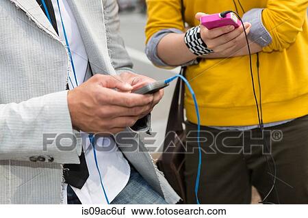 Stock Image - Close up of hands using mp3 player. Fotosearch