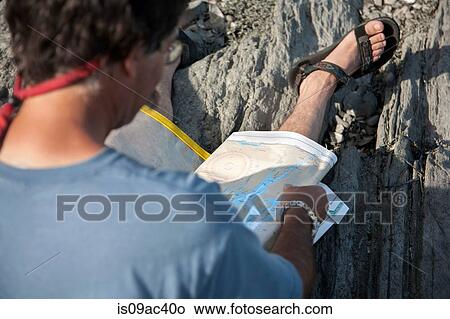 Close up of mature man sitting on rocks looking at maps, Bath, Maine, USA View Large Photo Image Picture - Close up of mature man sitting on rocks looking at maps, Bath, Maine, USA. Fotosearch