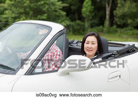 Stock Image - Couple enjoying leisurely drive in sports car. Fotosearch