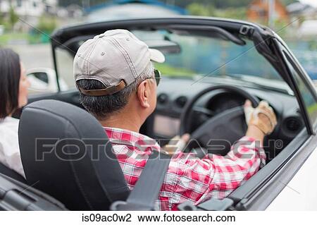 Stock Image - Couple enjoying leisurely drive in sports car. Fotosearch