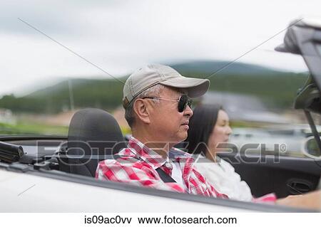 Stock Photo - Couple enjoying leisurely drive in sports car. Fotosearch