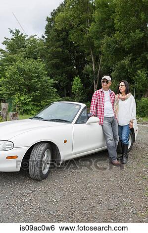 Couple standing beside car View Large Photo Image Stock Photograph - Couple standing beside car. Fotosearch
