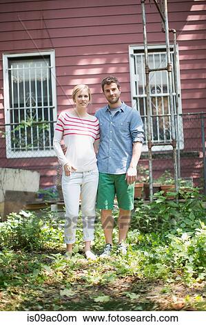 Picture - Couple standing outside house in garden. Fotosearch