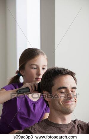 Stock Image - Daughter brushing father's hair. Fotosearch