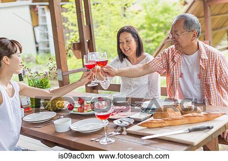 Picture - Family toasting at dining table. Fotosearch