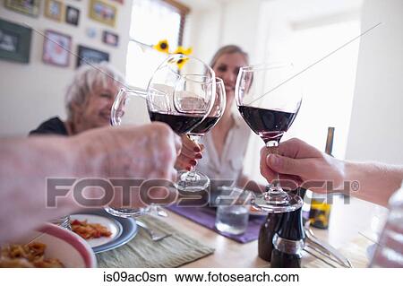 Picture - Family toasting with red wine at dinner table. Fotosearch