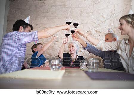 Stock Photo - Family toasting with red wine at dinner table. Fotosearch