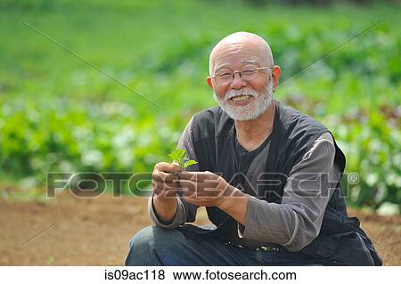 Farmer with leaf smiling at camera View Large Photo Image Stock Photo - Farmer with leaf smiling at camera. Fotosearch