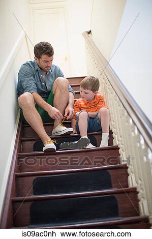 Father and son sitting on stairs tying shoelaces View Large Photo Image Stock Image - Father and son sitting on stairs tying shoelaces. Fotosearch