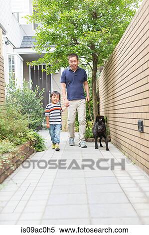 Stock Photography - Father and son walking dog on path. Fotosearch
