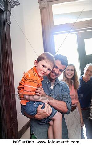 Stock Image - Father holding son in hallway, smiling. Fotosearch