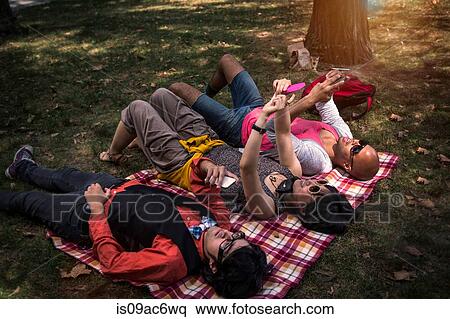 Stock Photography - Friends lying on blanket in park. Fotosearch