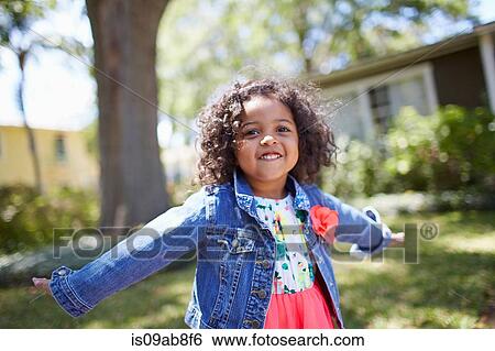 Stock Photograph - Girl standing in garden with arms wide. Fotosearch