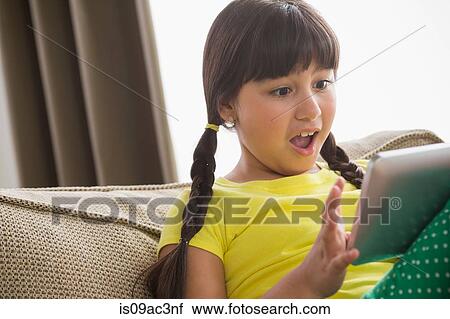 Stock Image - Girl using digital tablet with shocked expression. Fotosearch