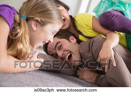 Stock Image - Girls tickling father. Fotosearch