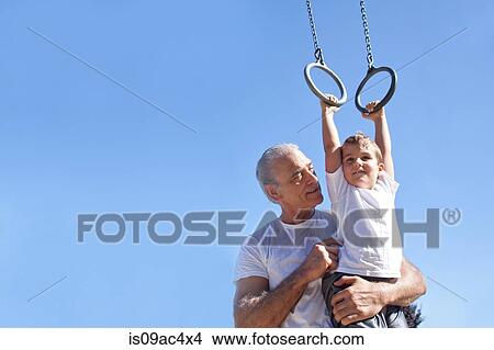 Picture - Grandfather holding grandson on gymnastic rings. Fotosearch