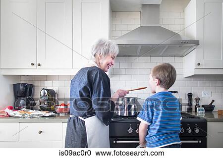 Stock Image - Grandmother and grandson preparing food at home. Fotosearch