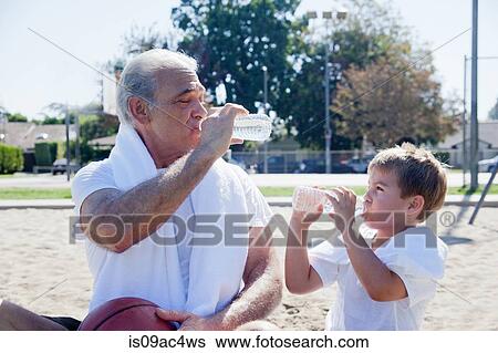 Man and grandson drinking bottled water together View Large Photo Image Stock Photograph - Man and grandson drinking bottled water together. Fotosearch