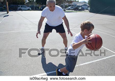 Stock Image - Man and grandson playing basketball. Fotosearch
