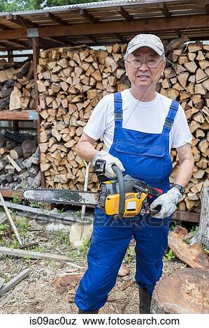 Stock Photo - Man carrying chainsaw. Fotosearch
