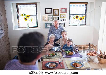 Man photographing family at meal time View Large Photo Image Stock Image - Man photographing family at meal time. Fotosearch