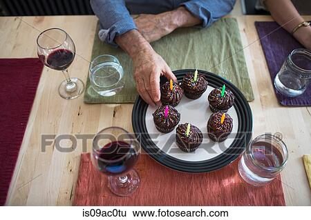 Stock Photograph - Man taking birthday cupcake from plate. Fotosearch