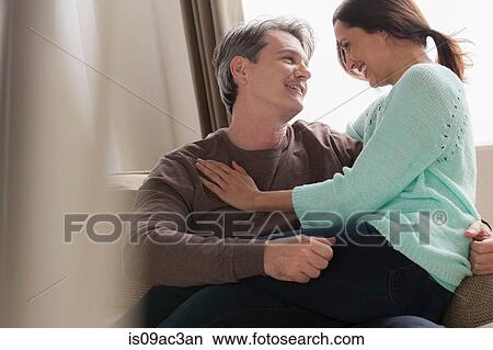 Picture - Mature couple hugging on sofa. Fotosearch