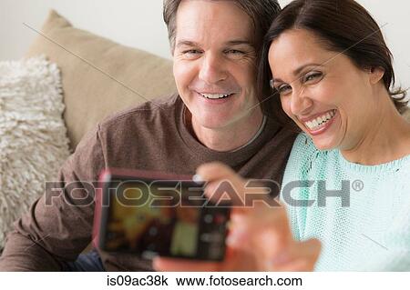 Stock Image - Mature couple photographing themselves with digital camera. Fotosearch