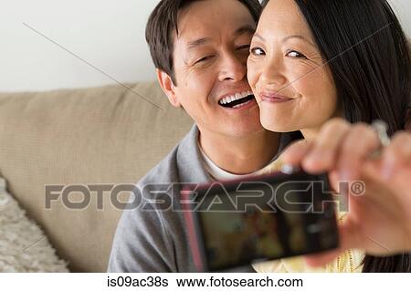 Stock Photograph - Mature couple photographing themselves with digital camera. Fotosearch
