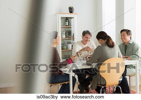 Stock Photo - Mature friends enjoying meal together. Fotosearch