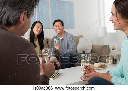 Stock Photograph - Mature friends socialising with white wine. Fotosearch